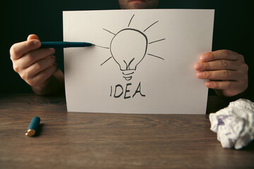 Businessman drawing a lightbulb on paper, concept of idea © Artvibe