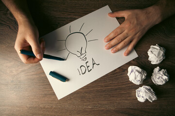 Businessman drawing a lightbulb on paper, concept of idea © Artvibe