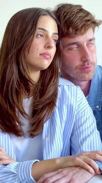 Disengaged young couple sitting together, showing clear signs of boredom and unhappiness as they avoid eye contact, highlighting a moment of crisis and disconnection in their relationship