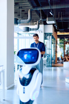Employee interacting with an artificial intelligence service robot, representing future workforce, automation, and technology in a modern office