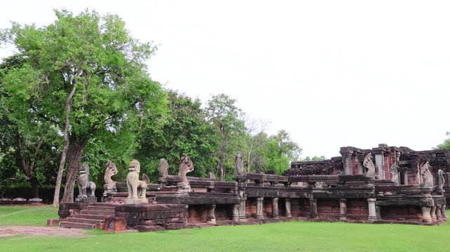Historic Phimai Historical Park sandstone ruins showing Naga bridge as a metaphoric pathway to heaven with wind blowing green trees in background