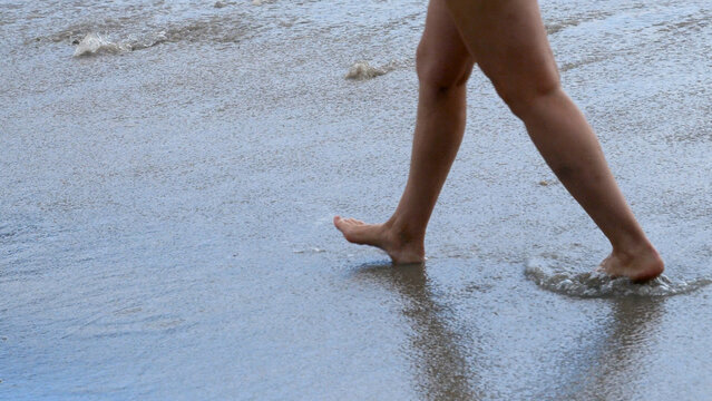 Woman walking barefoot summer beach. Relaxation Travel woman foot walking tropical summer beach. Close up legs walk along wave of sea water sand beach. Enjoy freedom barefoot leg walk outdoor