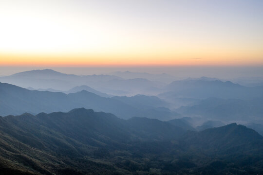 Layered mountain ranges fading into misty blue horizon at dawn