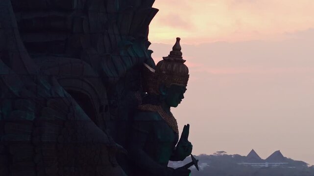 Indonesia cultural landmark Lord Vishnu Hindu sculpture close up at Garuda Wisnu Kencana park in Bali featuring detailed copper artwork and golden crown in warm sunset light aerial drone view
