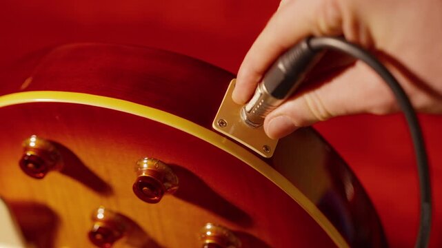 Slow motion shows an audio cable being unplugged from an electric guitar.