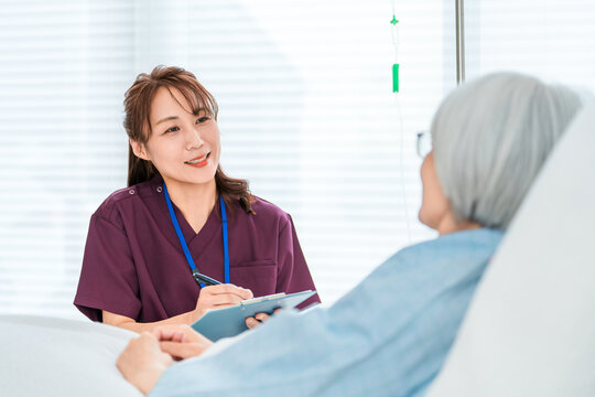 回診でヒアリングする医者,看護師の女性と入院患者のシニア女性