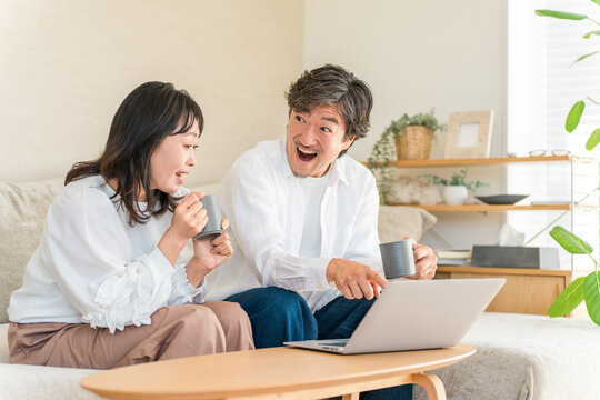 パソコンでお買い得情報を見つけて驚いた表情をする夫婦