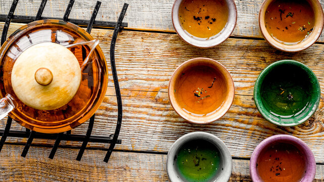 Set for tea ceremony. Glass teapot and ceramic cups on rustic wooden background top view