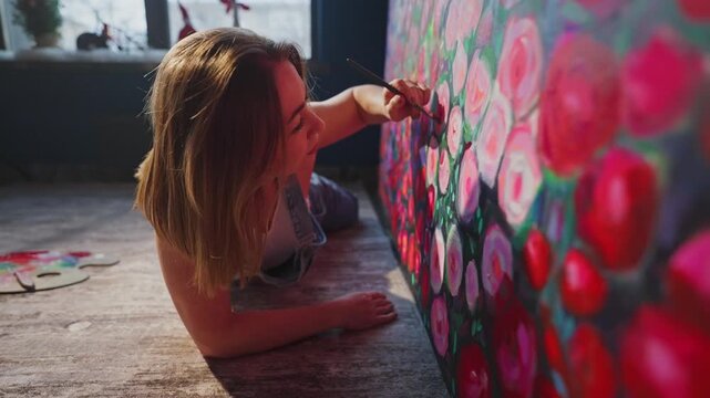 Artist paints vibrant roses on a large canvas. Sunlight streams through the window behind her. She focuses deeply on each petal. Creative passion flows through her brushstrokes
