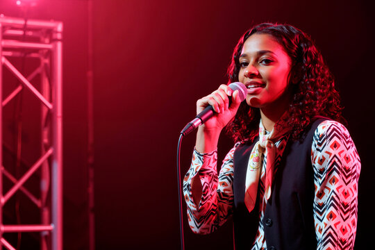 Portrait of teenage girl singing into microphone on stage, performing live music and youth talent concept. Useful for entertainment marketing, concert promotion, casting ads