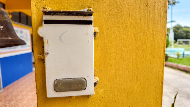 Detailed Close-Up of White Doorbell on Bright Yellow Wall