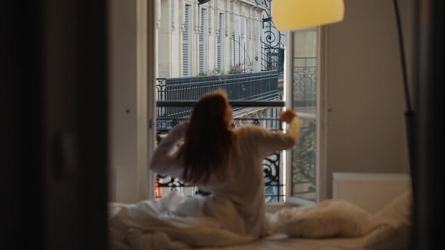 Redhead woman waking up and stretching in a parisian bedroom