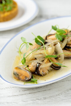 Midye pilaki, Turkish mussel meze with onions and microgreens on white plate