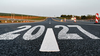 Fototapeta premium Road marking showing 2027 upcoming year in open landscape with clear sky and distant hills