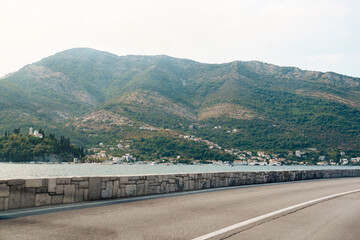 Fototapeta premium Mountain view along a road near water with houses in the distance at sunset