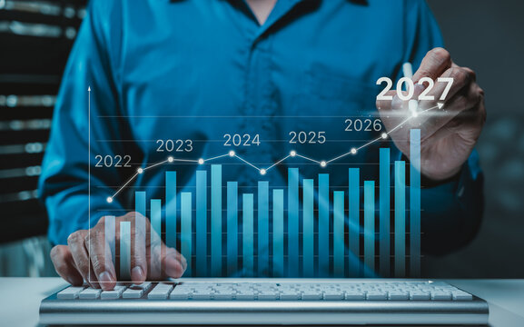 The 2027 New Year business goals concept. Businessman analyzes graph of trend market growth in 2027 and plans business growth and profit increases. calculates financial data for long-term investments.