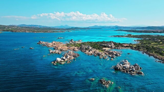 Aerial view over Spiaggia Testa del Polpo coastline. Rocky coves, clear turquoise water and distant islands create a scenic Sardinian island panorama.
