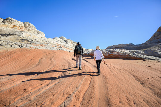 Tourists climbing up the red rocks under a clear blue sky. White Pocket. Vermilion Cliffs National Monument. Arizona. USA.