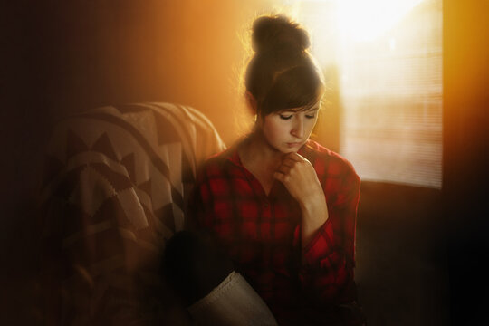Pensive young woman sitting alone in golden sunlight