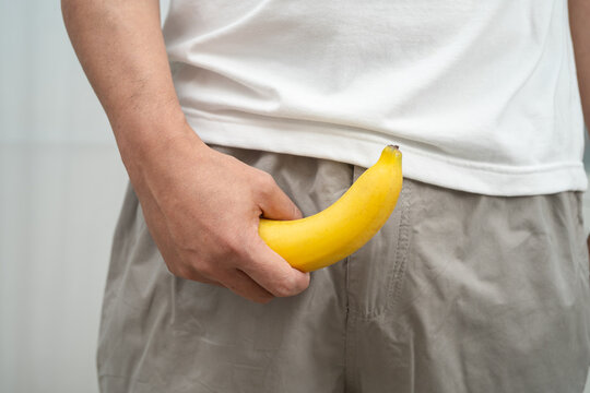 Male stands holding a banana, penis health.