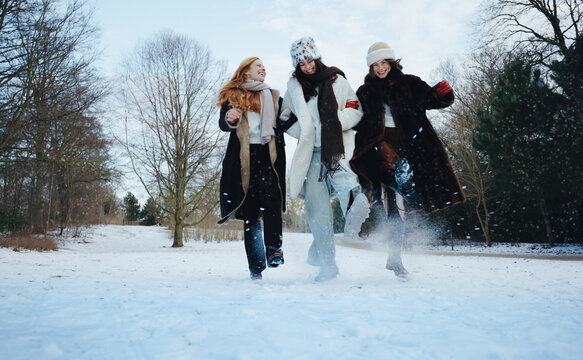 Walking through snow, women share laughter at the park