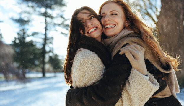 Laughing women hug during a sunny winter outing