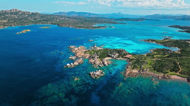 Aerial view of Spiaggia Testa del Polpo in Sardinia. Rocky shoreline, bright blue water and green coastal terrain create a beautiful La Maddalena beach landscape.