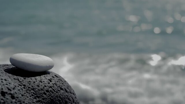 Single white pebble on black volcanic rock by sea.