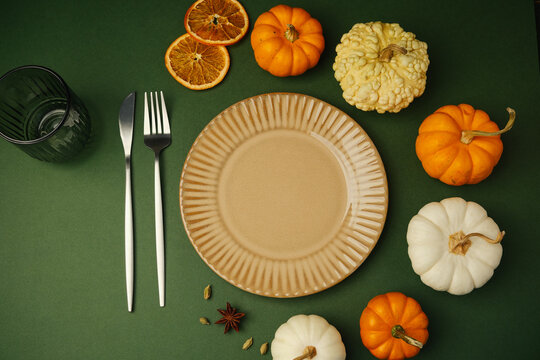 Table setting with pumpkins and dried oranges on a green background