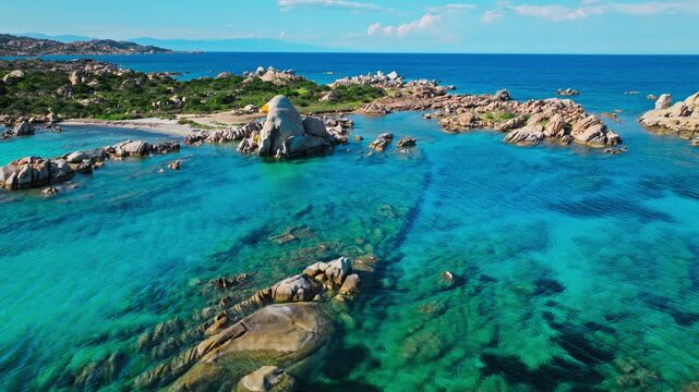 Aerial view of Spiaggia Testa del Polpo in La Maddalena. Rocky islets, crystal-clear water and shallow turquoise sea create a beautiful Mediterranean coastal scene.
