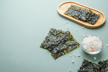 Crispy nori seaweed snack with salt on green background © reddish
