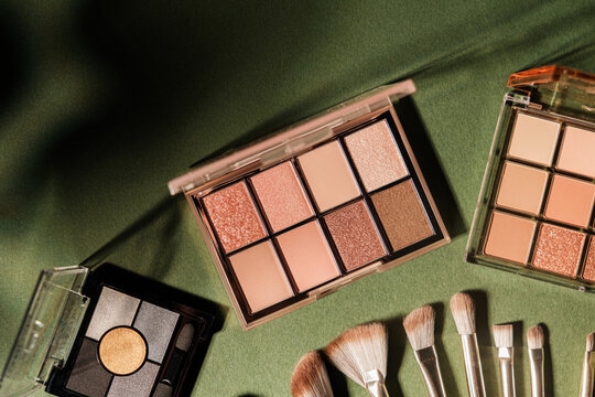 24-s-0-72.jpg Eye shadow palettes and makeup brushes arranged on a textured green background