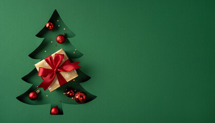 Merry Christmas and Happy New Year gift on cutout Christmas tree with red ornaments and ribbon on...