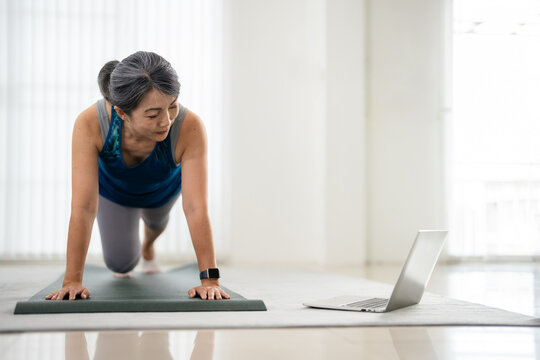 Fitness workout at home. woman watching and following excercise tutoria online on laptop computer.