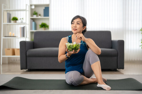 Healthy woman having salad after work out at home, sport and healthy food lifestyle concept.
