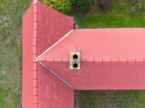 Top-down drone inspection view of a newly installed roof seen on an old English cottage. The old brick-built chimney has also been repointed.