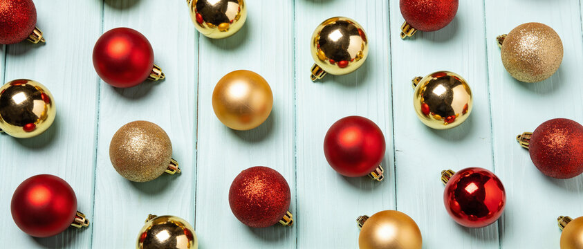 Red and gold christmas baubles scattered on a light blue wooden background