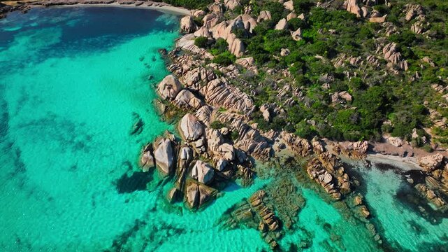 Aerial view over Spiaggia Testa del Polpo in La Maddalena. Granite rocks, turquoise shallows and Mediterranean vegetation create a scenic natural coastal view.