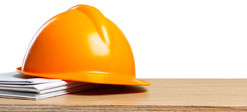 Construction hard hat and documents on a wooden table in a work setting