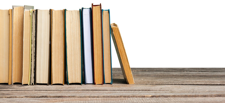 Books lined up on a wooden table with one book slightly apart from the others