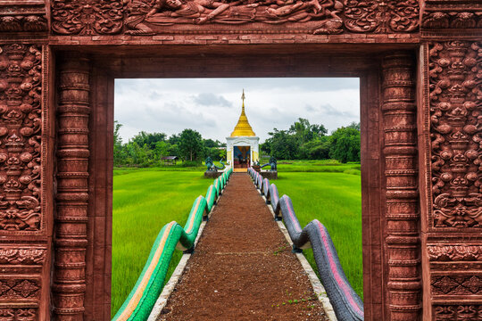 A sacred Buddha footprint situated in the middle of a lush green rice paddy field in Sakon Nakhon province, northeastern Thailand.