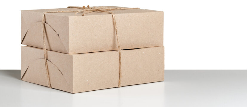 Brown cardboard boxes tied with twine placed on a white surface in a simple indoor setting