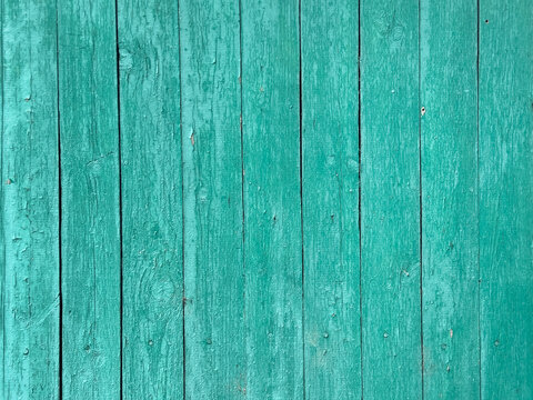 Weathered turquoise wooden plank wall with peeling paint and visible wood grain knots for textured background or rustic decor use