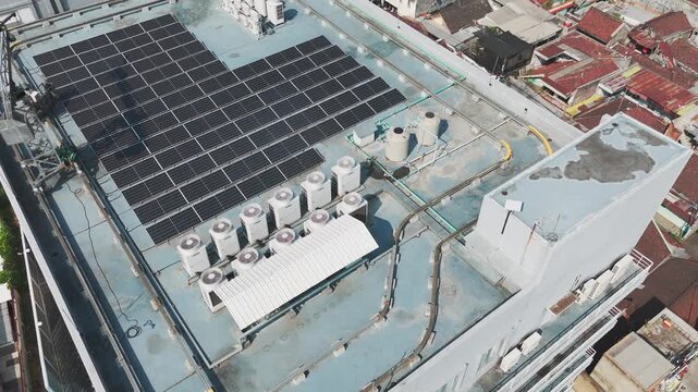 Aerial view of solar panels and HVAC units installed on a building rooftop in Malang, East Java, Indonesia.