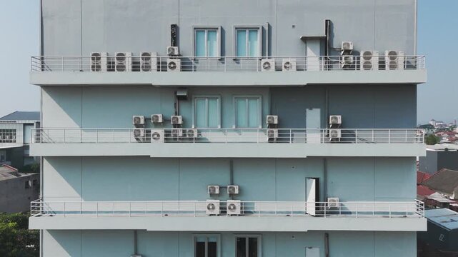 Aerial view of a multi-story building featuring numerous air conditioning units mounted on balconies in Malang, East Java, Indonesia.