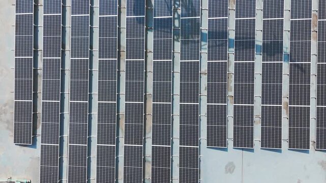 Aerial view of rows of solar panels and industrial air conditioning units installed on a flat rooftop in Malang, East Java, Indonesia.