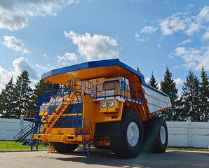 Smalyavichy, Belarus - June 14, 2025: Belaz huge dump truck parked with blue sky and trees in background © Slepitssskaya