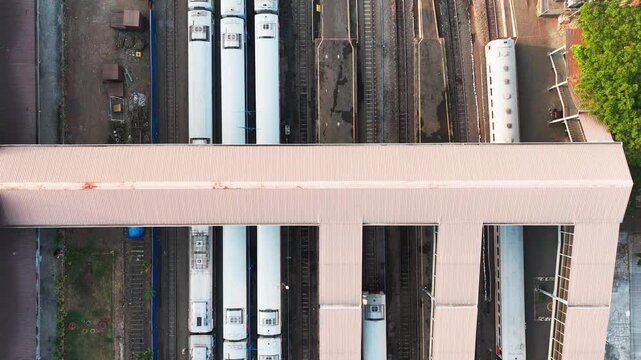 Aerial view of white passenger trains parked at a railway station with a pedestrian overpass structure in Malang, East Java, Indonesia.