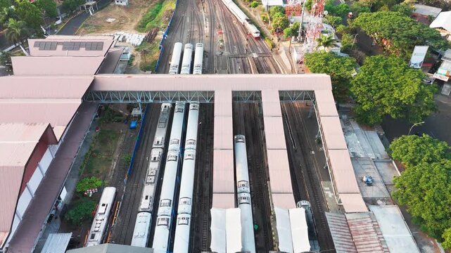 Aerial view of train station with multiple tracks and passenger trains parked at platforms in Malang, East Java, Indonesia.
