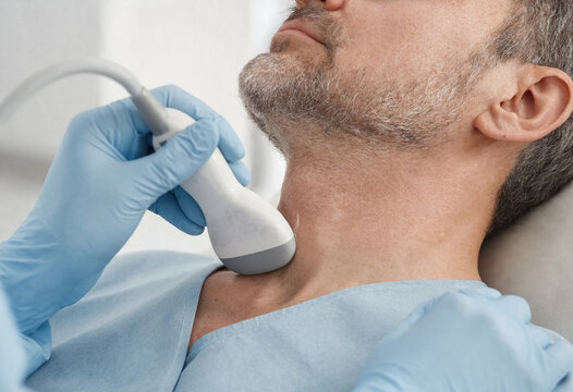 Adult man receives a neck ultrasound examination from a medical professional in a clinical setting. The procedure supports diagnostic healthcare and medical screening.